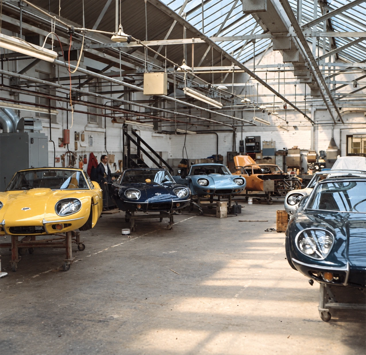 AI-enhanced archive photograph of the Marcos factory floor in the 1960s, with GT coupés in mid-assembly